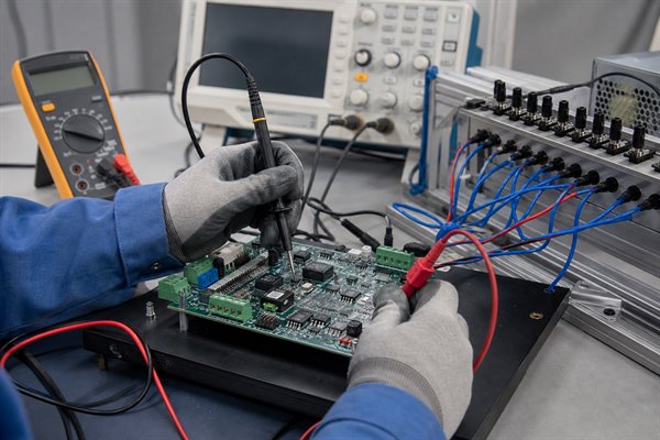 Engineer testing analog and digital input channels on a mixed-signal PCB at a validation bench