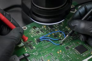 PCB jumper inspection under magnification with electrical probes checking completed connections