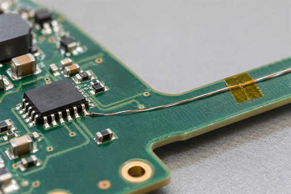Fine-wire thermocouple junction attached to a component lead with flat routing and tape strain relief